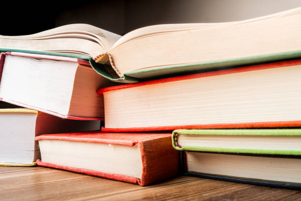 istock Stacked educational books on a wooden surface with sunlight highlighting their colorful spines 2182551507