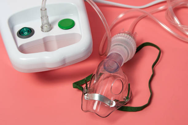istock A white medical inhalation device with a green button and a clear plastic mask with a green strap 2182553420