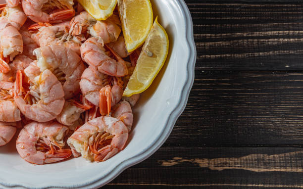 istock Boiled king prawns in deep bowl with lemon close up view on dark table 2182557659