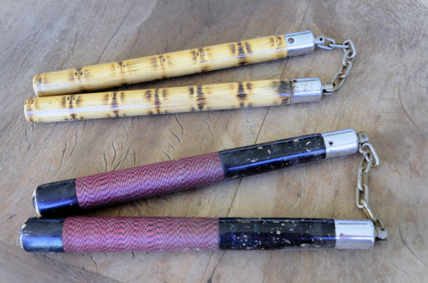 Red and black nunchaku and another one with a solid wood bamboo appearance