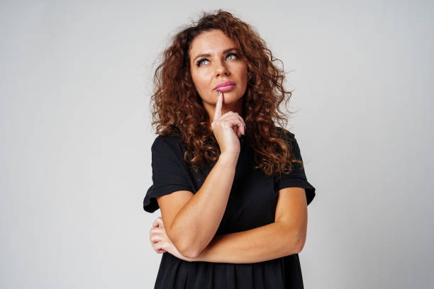 istock Thoughtful woman pondering ideas against a neutral background 2182565928