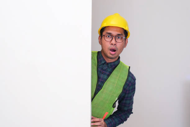 istock Asian civil engineer peeking from behind a wall showing shocked face expression 2182567921