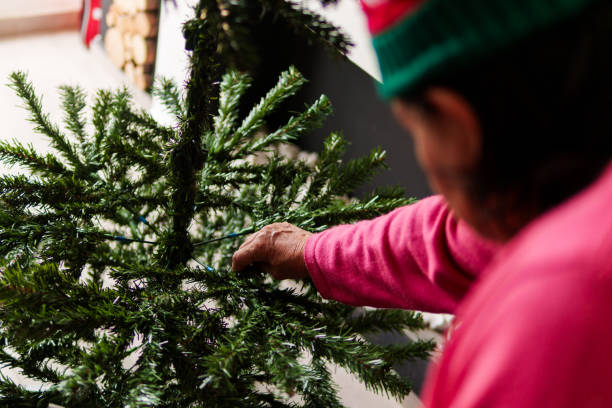 A person is decorating a Christmas tree with green branches