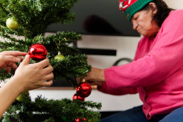 istock A woman is decorating a Christmas tree with red and green ornaments 2182578080