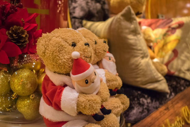 The stuffed bear sits on top of the gifts wrapped neatly by the Christmas tree.