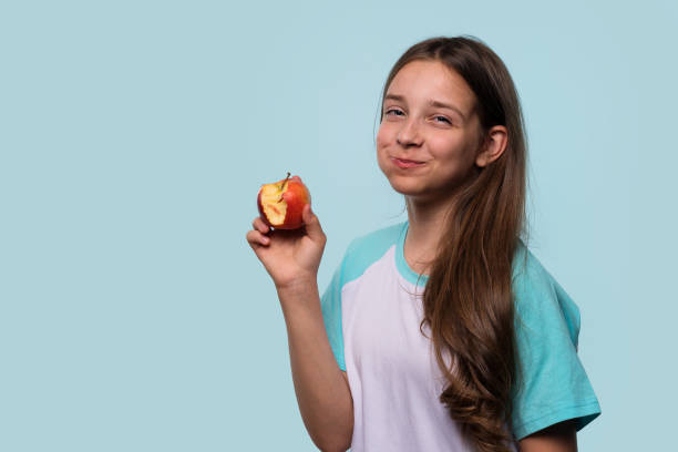 istock Girl smiles mischievously while holding an apple 2182593056
