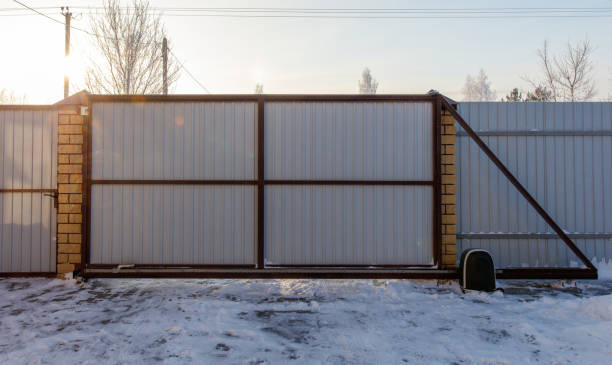 A gate is open and the snow is piled up on the ground