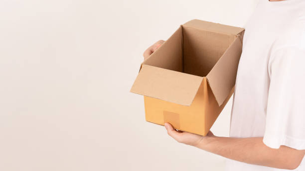 istock Hand holding cardboard box on empty background. Concept for transportation, online shopping, celebration and gift giving on special day. 2182594504