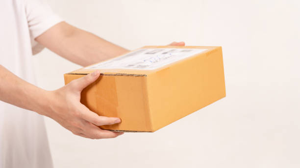 istock Hand holding cardboard box on empty background. Concept for transportation, online shopping, celebration and gift giving on special day. 2182594674