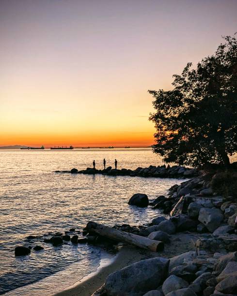 Sunset at Beach with silhouette of three people, Vancouver, BC