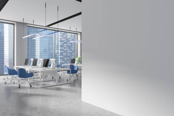 istock Coworking interior with desks and pc computers near window. Mockup wall 2182598896