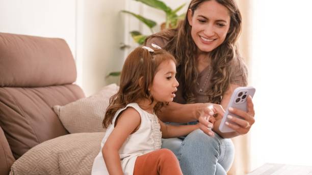 istock Happy mother and girl using cellphone on sofa at home 2182607555