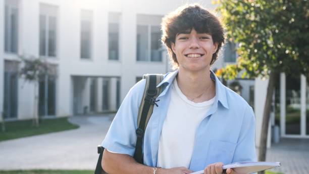 istock Smiling young male student holding book on university campus 2182608458