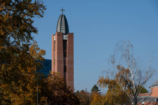 istock Church tower with clock and cross in autumn setting 2182609307