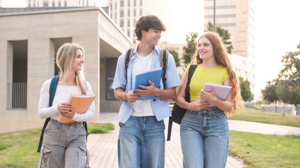 istock Happy university students with notebooks walking on campus 2182609693
