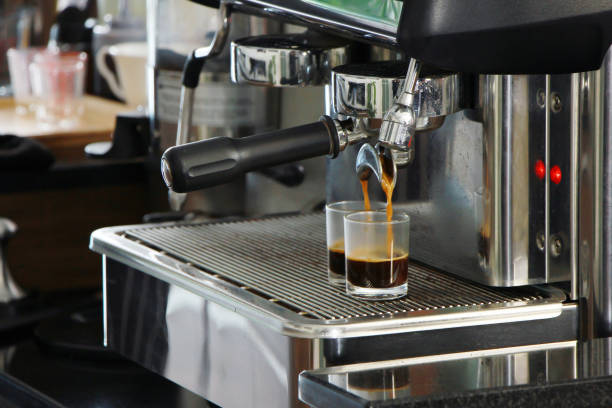 istock Freshly brewed espresso pours from a professional coffee machine into a glass cup on counter bar in cafe 2182612120