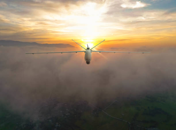 Silhouette of spy drone (UAV) flying over the clouds at sunset. stock photo
