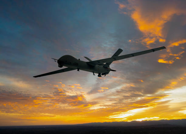 istock Silhouette of spy drone (UAV) flying over the clouds at sunset. 2182612626