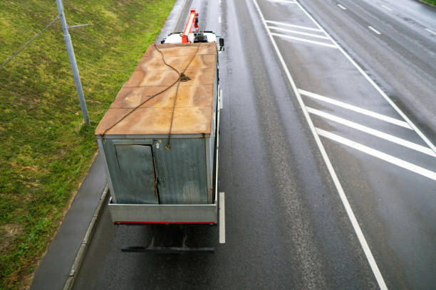 istock truck-mounted crane transporting a metal workers' cabin. The scene emphasizes logistics, industrial transport, and efficient relocation of resources in construction 2182615706