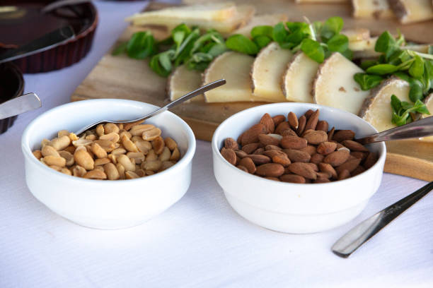 Buffet table offering bowls of peanuts and almonds alongside cheese and greens, creating a varied and healthy snacking option