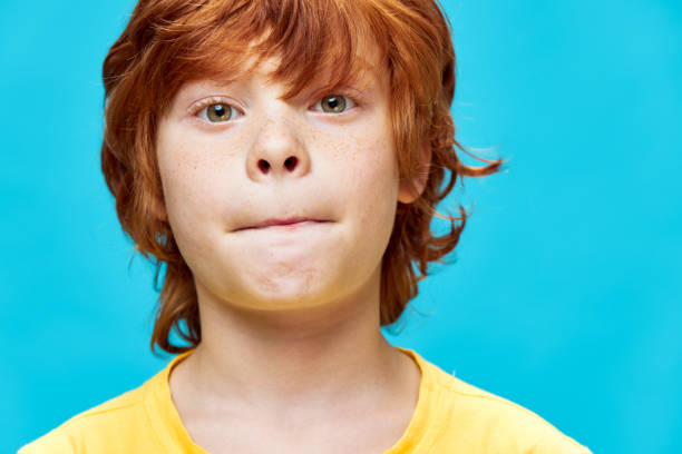 istock Red-haired boy face close-up closed lips blue background 2182632457