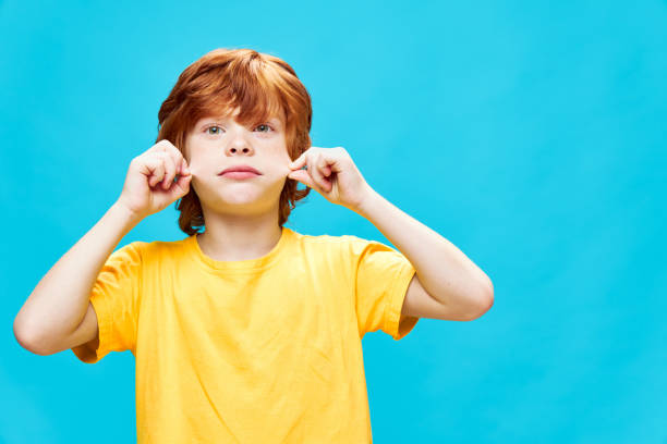 istock redhead boy holding cheeks with hands cropped view yellow t-shirt 2182633025