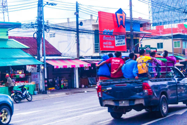 Phuket,Thailand-May 6th 2024:View of busy route 402 expressway traffic near Royal Phuket Marina ,traditional motorbikes and people workers who ride in open pickup trucks