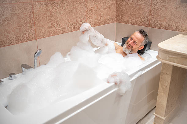 istock A mature man with a white beard is enjoying a bath in a bathroom. 2182641926