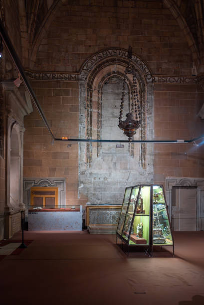 A historical interior showcasing a display case filled with artifacts in a dimly lit chapel during the evening hours, highlighting architectural features and ambiance of the space