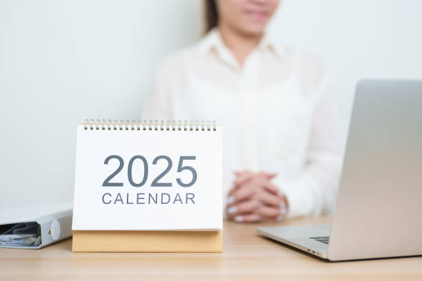 istock 2025 Year Calendar on table with business woman using laptop computer, working and writing in office. countdown, Happy New Year, Resolution, Year End and New Start and Goals Plan Action Concept 2182658558