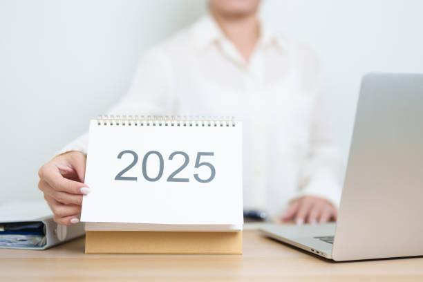 istock 2025 Year Calendar on table with business woman using laptop computer, working and writing in office. countdown, Happy New Year, Resolution, Year End and New Start and Goals Plan Action Concept 2182658564