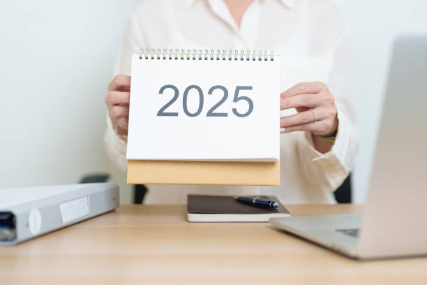istock 2025 Year Calendar on table with business woman using laptop computer, working and writing in office. countdown, Happy New Year, Resolution, Year End and New Start and Goals Plan Action Concept 2182658567