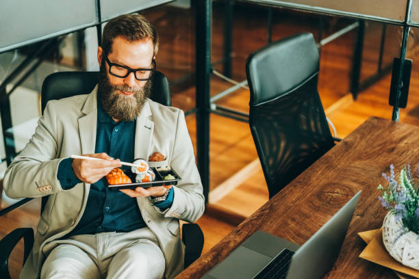 istock Businessman eating sushi in the office 2182662502