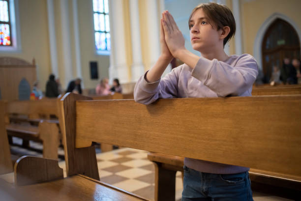istock Catholic boy kneeling praying to god in temple 2182664124