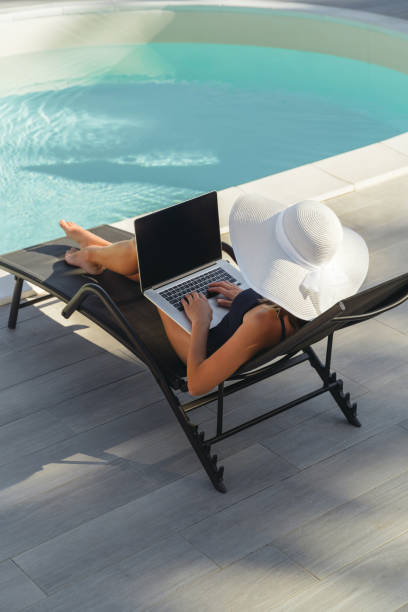 istock Woman working on laptop by the pool 2182664769