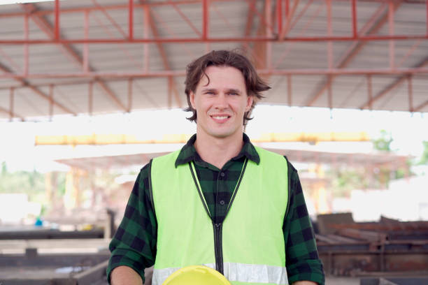 portrait of good looking caucasian white technician or worker in the factory looking at camera and smiles. Happy cheerful foreman or worker in manufacturing factory smiling.