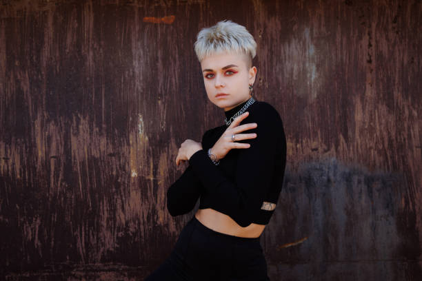 istock Blonde model with colorful visage posing in black outfit on rusty brown background 2182666548