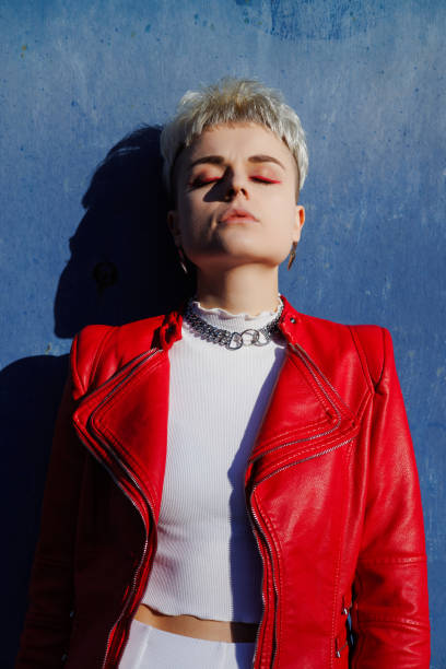 istock Stylish woman with bright makeup wearing red leather jacket on textured blue background 2182667963