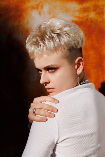 istock Stylish blonde woman in white turtleneck posing on rusty background with sunlight 2182669395