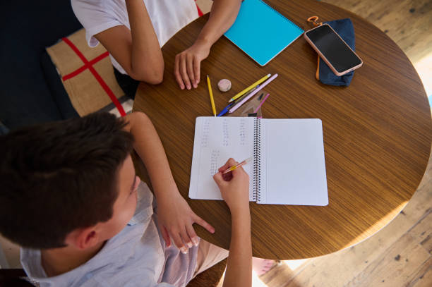 istock Top view of children doing homework at wooden table with notebooks 2182673816