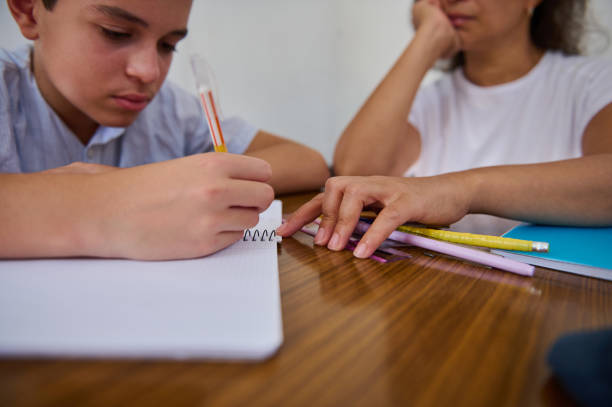 istock Focused child studying with mentor at home learning desk 2182673842
