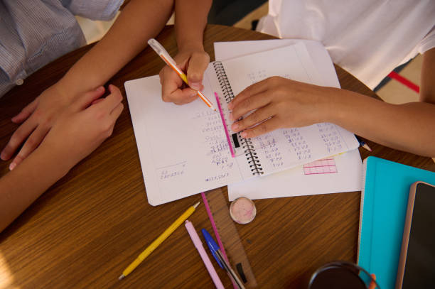 istock Students collaborate on math homework at wooden desk 2182673905