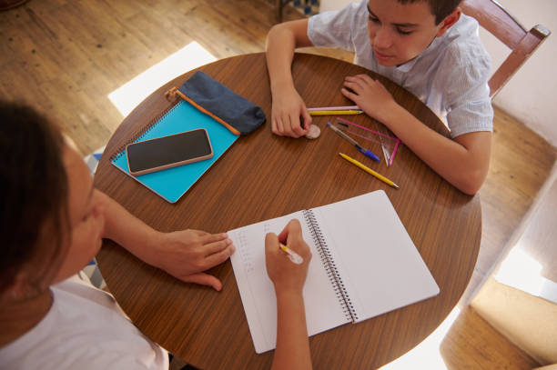 istock Mother and son doing homework together at a wooden table 2182673963