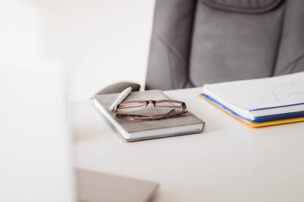 Planner, a pen and eyeglasses lying on an office desk
