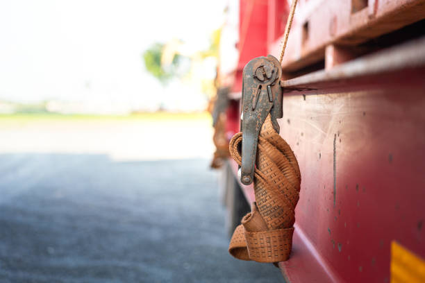 Close-up at locking device of safety latching strap that using for secure equipment or heavy object that transport on trailer truck. Transportation industrial equipment object, selective focus.