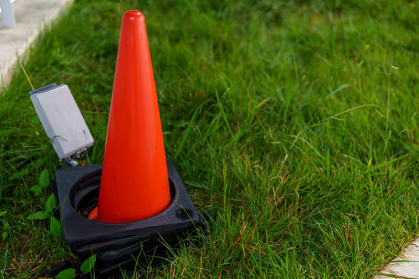 red plastic traffic cone on green grass field lawn with silver color reflective strip