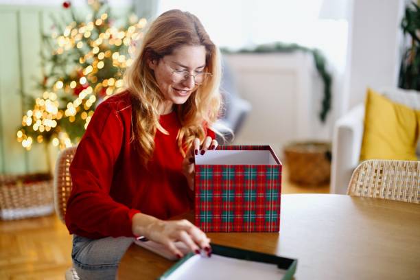 istock Lovely young female opening her Christmas present 2182687770
