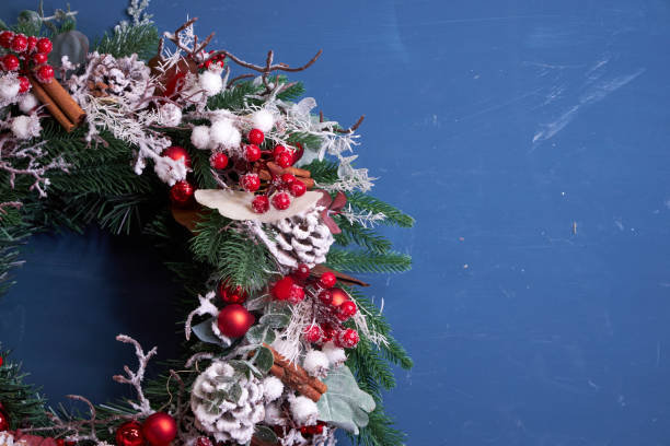istock Christmas pine needle wreath with red decoration on blue background 2182688673