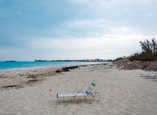 Beach scene with sand, clouds and water.