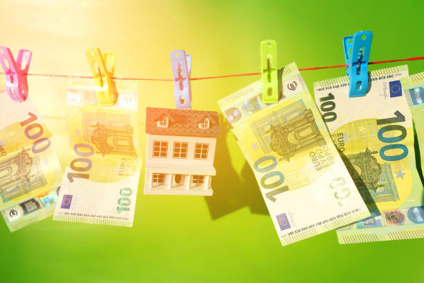 Money Laundering through Real Estate. Washed Euro note paper during drying. House and One hundred 100 euros Banknote are drying on clothesline. Money Laundering Risks in Real Estate, financial crime.